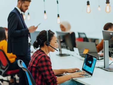 Masaüstü bilgisayarlar, dizüstü bilgisayarlar üzerinde çalışan ve fikirlerini modern bir ofis alanında paylaşan çok ırklı çalışma arkadaşları. Genç nüfuzlu kişiler çevrimiçi pazarlama projeleri üzerinde çalışıyorlar