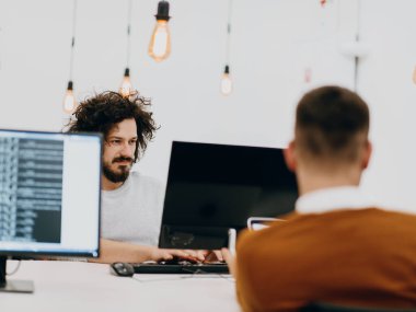 Masaüstü bilgisayarlar, dizüstü bilgisayarlar üzerinde çalışan ve fikirlerini modern bir ofis alanında paylaşan çok ırklı çalışma arkadaşları. Genç nüfuzlu kişiler çevrimiçi pazarlama projeleri üzerinde çalışıyorlar