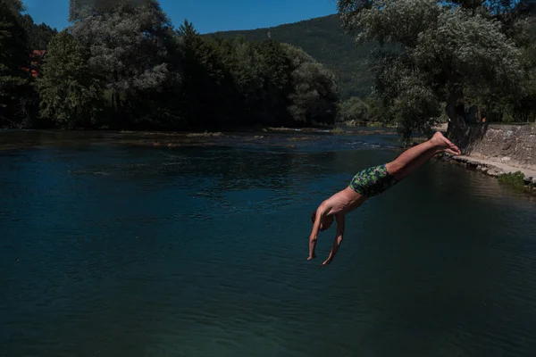 젊은이는 강으로 뛰어내려 수영을 준비를 여름휴가를 즐기고 고품질 — 스톡 사진
