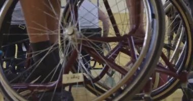 Tekerlekli sandalyede oturan ve spor salonunda basketbol oynayan engelli bir sporcunun yakın çekimi. Seçici odaklanma. Yüksek kalite 4K video. 