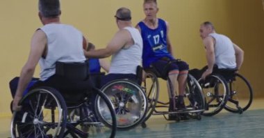 Tekerlekli sandalyede oturan ve spor salonunda basketbol oynayan engelli bir sporcunun yakın çekimi. Seçici odaklanma. Yüksek kalite 4K video. 