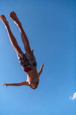 Genç adam temiz nehre atlamaya hazırlanıyor, yüzüyor, yaz tatillerinde vakit geçiriyor. Yüksek kalite fotoğraf