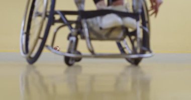 Tekerlekli sandalyede oturan ve spor salonunda basketbol oynayan engelli bir sporcunun yakın çekimi. Seçici odaklanma. Yüksek kalite 4K video. 