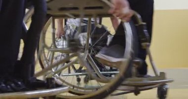 Tekerlekli sandalyede oturan ve spor salonunda basketbol oynayan engelli bir sporcunun yakın çekimi. Seçici odaklanma. Yüksek kalite 4K video. 