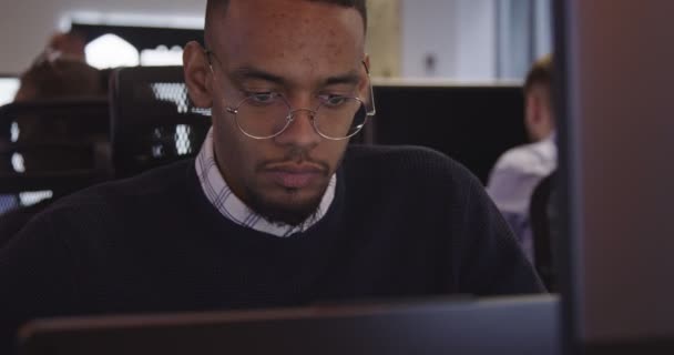 年轻的非裔美国商人或软件工程师 戴着眼镜 坐在现代化的同事办公室里 在电脑上工作 高质量的照片 — 图库视频影像