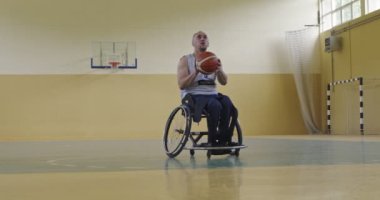 Modern bir spor salonunda tek başına basketbol oynayan engelli biri. Engelli biri için spor ve dahil etme kavramı. Seçici odaklanma yavaş çekim. Yüksek kaliteli 8K görüntü
