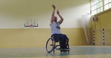 Modern bir spor salonunda tek başına basketbol oynayan engelli biri. Engelli biri için spor ve dahil etme kavramı. Seçici odaklanma yavaş çekim. Yüksek kaliteli 8K görüntü
