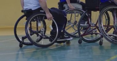 Tekerlekli sandalyede oturan ve spor salonunda basketbol oynayan engelli bir sporcunun yakın çekimi. Seçici odaklanma. Yüksek kalite 4K video. 