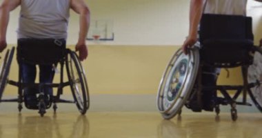 Tekerlekli sandalyede oturan ve spor salonunda basketbol oynayan engelli bir sporcunun yakın çekimi. Seçici odaklanma. Yüksek kalite 4K video. 
