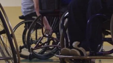 Tekerlekli sandalyede oturan ve spor salonunda basketbol oynayan engelli bir sporcunun yakın çekimi. Seçici odaklanma. Yüksek kalite 4K video. 