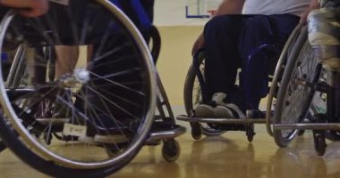 Tekerlekli sandalyede oturan ve spor salonunda basketbol oynayan engelli bir sporcunun yakın çekimi. Seçici odaklanma. Yüksek kalite 4K video. 