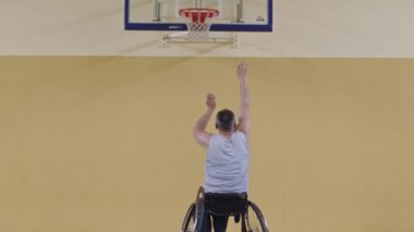Modern bir spor salonunda tek başına basketbol oynayan engelli biri. Engelli biri için spor ve dahil etme kavramı. Seçici odaklanma yavaş çekim. Yüksek kaliteli 8K görüntü