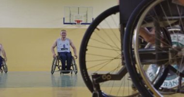 Tekerlekli sandalyede oturan ve spor salonunda basketbol oynayan engelli bir sporcunun yakın çekimi. Seçici odaklanma. Yüksek kalite 4K video. 