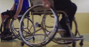 Tekerlekli sandalyede oturan ve spor salonunda basketbol oynayan engelli bir sporcunun yakın çekimi. Seçici odaklanma. Yüksek kalite 4K video. 