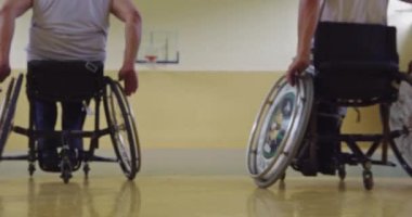 Tekerlekli sandalyede oturan ve spor salonunda basketbol oynayan engelli bir sporcunun yakın çekimi. Seçici odaklanma. Yüksek kalite 4K video. 