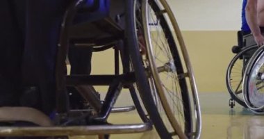 Tekerlekli sandalyede oturan ve spor salonunda basketbol oynayan engelli bir sporcunun yakın çekimi. Seçici odaklanma. Yüksek kalite 4K video. 