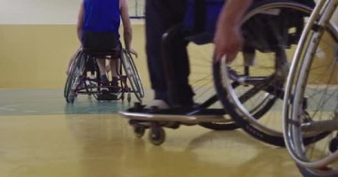 Tekerlekli sandalyede oturan ve spor salonunda basketbol oynayan engelli bir sporcunun yakın çekimi. Seçici odaklanma. Yüksek kalite 4K video. 