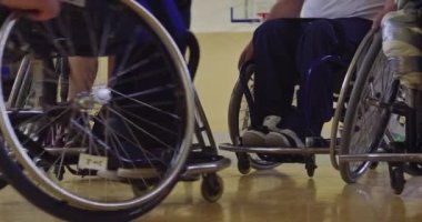 Tekerlekli sandalyede oturan ve spor salonunda basketbol oynayan engelli bir sporcunun yakın çekimi. Seçici odaklanma. Yüksek kalite 4K video. 