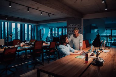  Modern bir ofis alanında, tekerlekli sandalyedeki bir iş adamı gece geç saatlerde bayan bir meslektaşıyla birlikte çalışıyor. Arka planda iş arkadaşları. Yüksek kalite fotoğraf