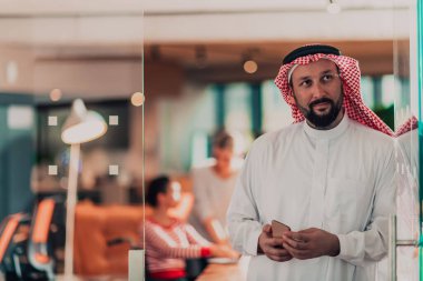 Ofisteki Orta Doğulu Arap işadamı ekibinin önünde akıllı telefondan konuşuyor. Yüksek kalite fotoğraf