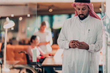 Ofisteki Orta Doğulu Arap işadamı ekibinin önünde akıllı telefondan konuşuyor. Yüksek kalite fotoğraf