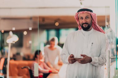Ofisteki Orta Doğulu Arap işadamı ekibinin önünde akıllı telefondan konuşuyor. Yüksek kalite fotoğraf