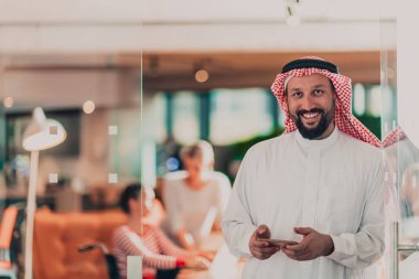 Ofisteki Orta Doğulu Arap işadamı ekibinin önünde akıllı telefondan konuşuyor. Yüksek kalite fotoğraf