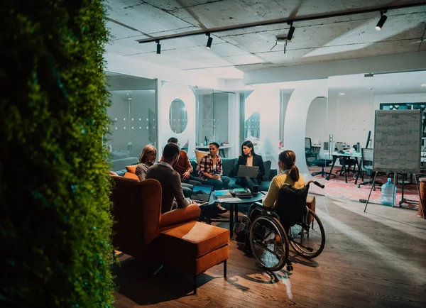 一个坐在轮椅上的女商人和团队在一个现代化的办公室举行商务会议 一群年轻的自由职业者就新的在线商务项目达成了一致 — 图库照片