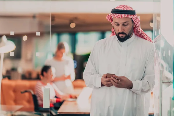 彼のチームの前でスマートフォンで話しているオフィスで中東アラブのビジネスマン 高品質の写真 — ストック写真