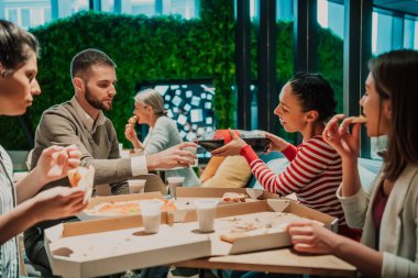 Ofiste farklı iş arkadaşlarıyla pizza yemek, mutlu çoklu etnik çalışanlar öğle yemeğinde birlikte eğlenmek, güzel sohbetler ve duygular..