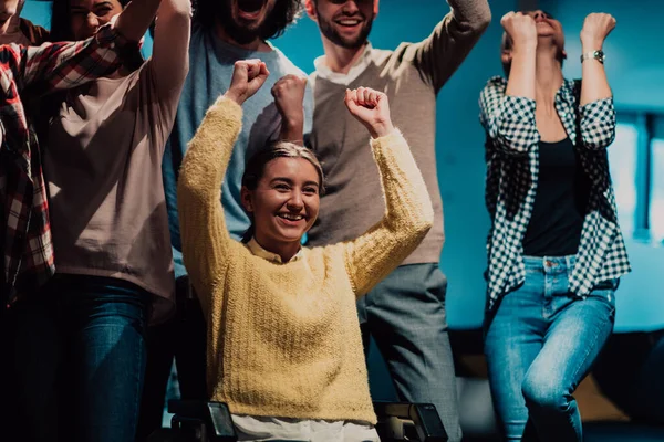 同僚と一緒に空中で手を挙げながら車椅子でビジネスの女性の写真 一緒にビジネスの成功を祝う — ストック写真