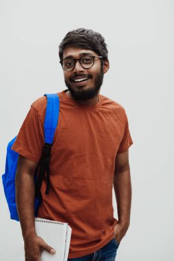  Mavi sırt çantalı, gözlüklü ve gri arka planda poz veren Hintli bir öğrenci. Eğitim ve eğitim kavramı. Okula geri dönme zamanı.. 