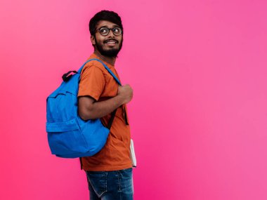  Mavi sırt çantalı, gözlüklü ve pembe arka planda poz veren Hintli bir öğrenci. Eğitim ve eğitim kavramı. Okula geri dönme zamanı.. 