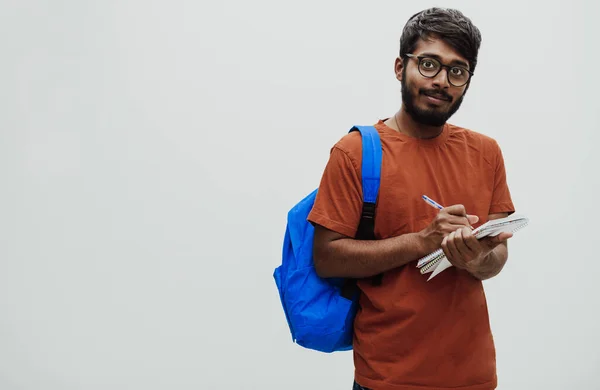 Индийский Студент Синем Рюкзаке Очках Блокноте Позирует Сером Фоне Концепция — стоковое фото