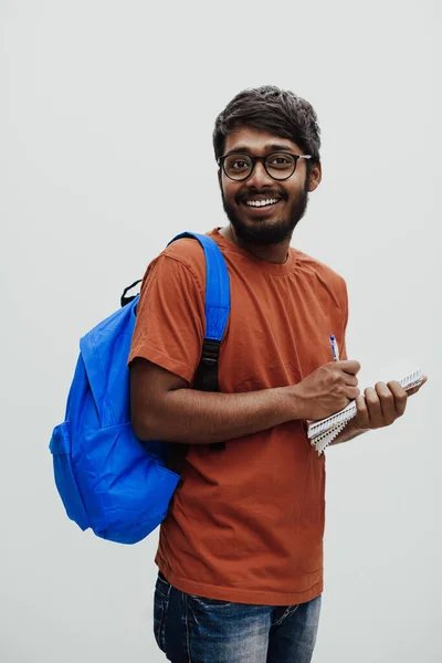 Indiska Student Med Blå Ryggsäck Glasögon Och Anteckningsbok Poserar Grå — Stockfoto