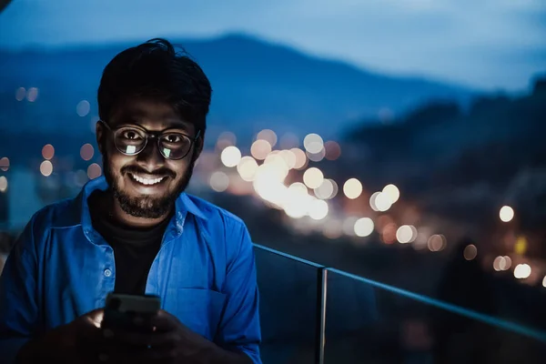 Indián Brýlemi Modrou Košilí Používá Noci Mobilní Telefon Balkóně Moderní — Stock fotografie