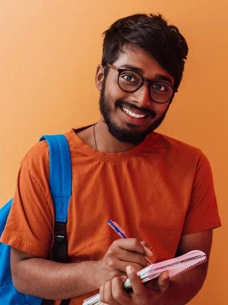 Indiska Student Med Blå Ryggsäck Glasögon Och Anteckningsbok Poserar Orange — Stockfoto