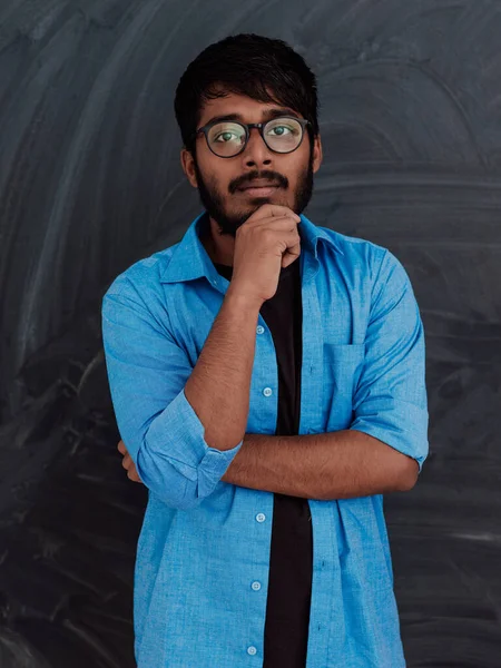 一位身穿蓝色衬衫 戴着一副眼镜的印度年轻人 若有所思地在学校董事会前摆姿势 — 图库照片