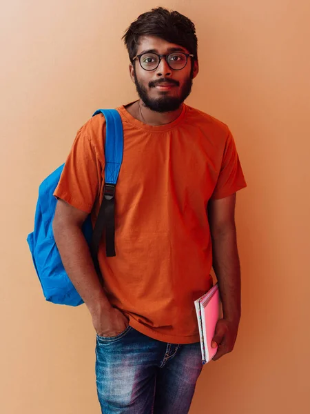 Индийский Студент Синем Рюкзаке Очках Блокноте Позирует Оранжевом Фоне Концепция — стоковое фото