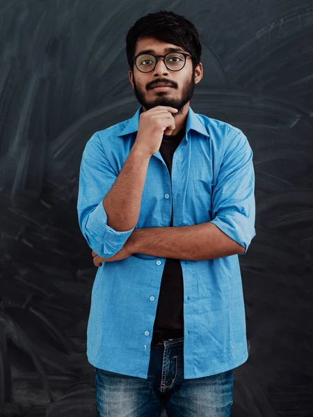 一位身穿蓝色衬衫 戴着一副眼镜的印度年轻人 若有所思地在学校董事会前摆姿势 — 图库照片