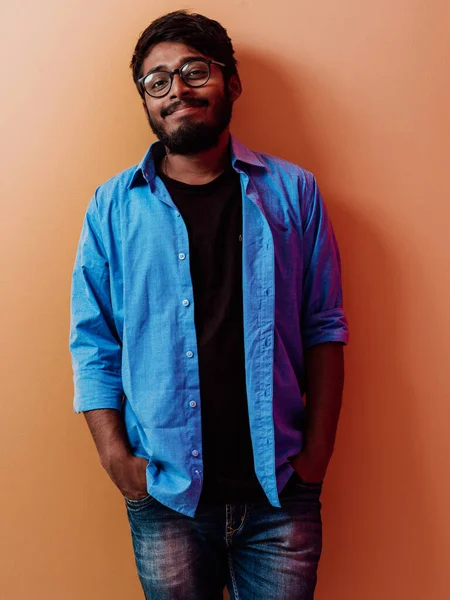 Индийский Улыбающийся Молодой Студент Голубой Рубашке Очках Позирует Оранжевом Фоне — стоковое фото