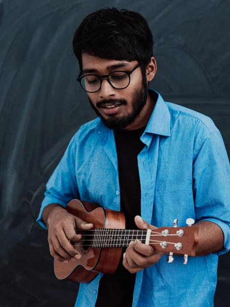 Индийский Юноша Синей Рубашке Очках Играет Гитаре Перед Школьной Доской — стоковое фото