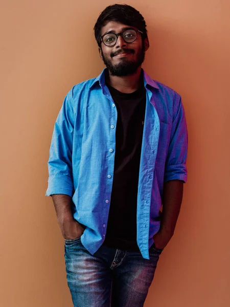 Индийский Улыбающийся Молодой Студент Голубой Рубашке Очках Позирует Оранжевом Фоне — стоковое фото