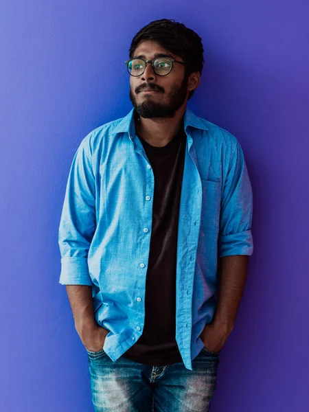 身穿蓝色衬衫 戴着紫色背景眼镜 面带微笑的印度年轻人 — 图库照片