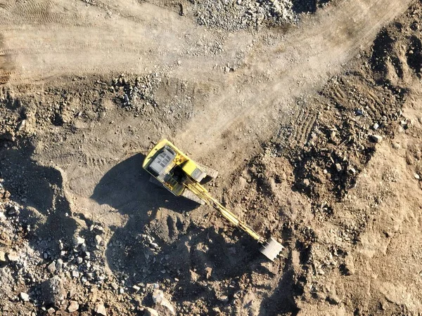 Industrial mine excavators are digging the soil in the construction site and loading trucks. Aerial drone top view. Hi quality 4K video.