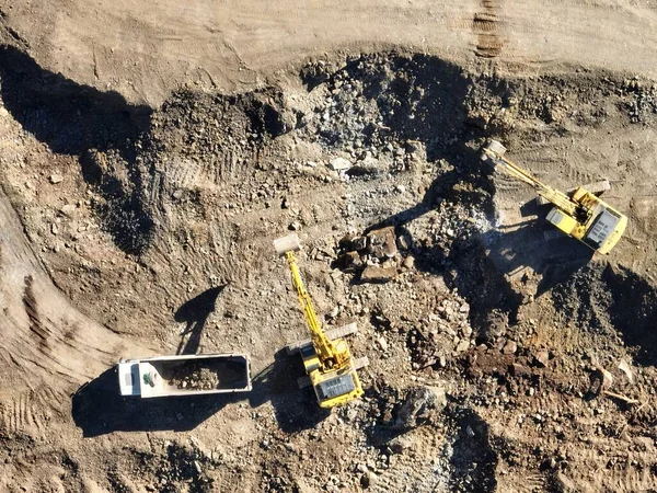 工業用鉱山掘削機は建設現場で土壌を掘り トラックをロードしています 空中ドローンのトップビュー 高品質4Kビデオ — ストック写真