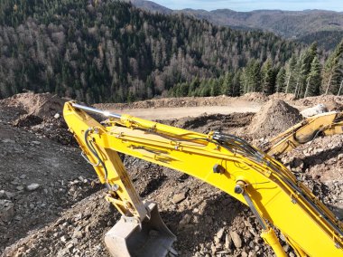 Endüstriyel maden kazıcıları inşaat alanındaki toprağı kazıyor ve kamyonları yüklüyor. Hava aracı üst görüntüsü. Merhaba kaliteli 4K video.