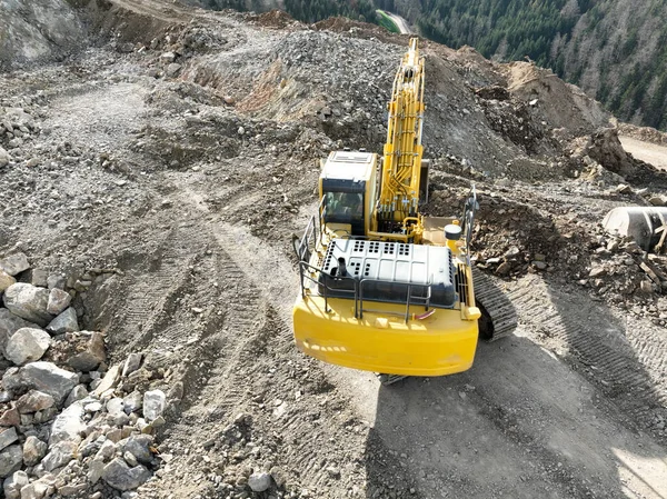 Industrial mine excavators are digging the soil in the construction site and loading trucks. Aerial drone top view. Hi quality 4K video.