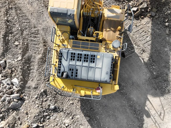Industrial mine excavators are digging the soil in the construction site and loading trucks. Aerial drone top view. Hi quality 4K video.