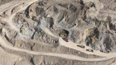 Endüstriyel maden kazıcıları inşaat alanındaki toprağı kazıyor ve kamyonları yüklüyor. Hava aracı üst görüntüsü. Merhaba kaliteli 4K video.
